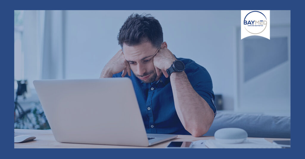 Man stressed in front of laptop.